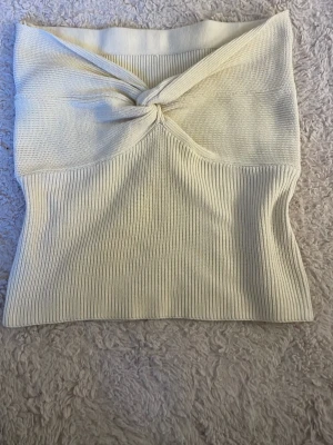 Ljusbeige ribbad tubtopp med twist - Snygg ljusbeige tubtopp med twistad detalj framtill och ribbad struktur. Toppen är ärmlös och har en bandeau-form som sitter tight och ger en clean look💗