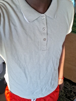 Beige polotopp med knappar - Säljer en enkel och stilren beige polotopp med klassisk krage och tre knappar framtill. Toppen har korta ärmar och är gjord i ett mjukt bomullsmaterial som känns skönt mot huden. Perfekt för dig som gillar en clean och avslappnad look.