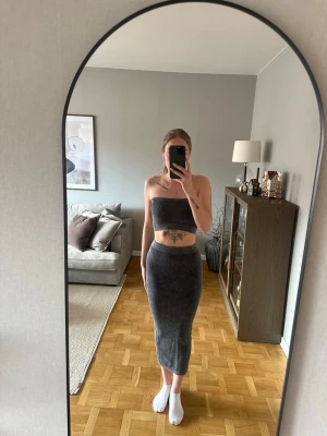 Mörkgrå bandeau topp med kjol - Snyggt sett med bandeau topp och långkjol i stentvättad svart/grå. Använd endast ett fåtal gånger. Säljs helst tillsammans. 