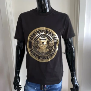 Balmain Paris T-Shirt, Svart, Storlek M - Helt ny, högkvalitativ replika . Skyltdockan på bilden är 175 cm lång och bär storlek S.  Pris: 899kr  Leverans: Skickas inom 24 timmar  Observera: Begränsat antal i lager – först till kvarn gäller  