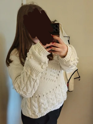 Vit stickad tröja - Säljer en vit chunky stickad tröja med breda ärmar och snyggt strukturmönster. Tröjan har rund halsringning och är oversize med ribbade muddar. Perfekt för dig som gillar en mysig och trendig look.