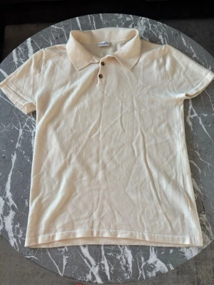 John Henric Pike  - Hör av er vid frågor kring produkt eller pris. Klassisk beige pikétröja från John Henric med korta ärmar. Tröjan har tre knappar framtill och är gjord i merino ull. Passar till det mesta och speciellt nu när våren och sommarn närmar sig. Helt fel fri inga som helst defekter, märken eller liknande på den.  OBS - Är storlek XL men tvättades av misstag i för högtemperatur så krympte till Small, men i topp topp skick.