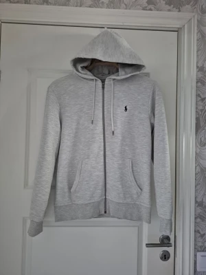 Ljusgrå hoodie från Polo Ralph Lauren - Säljer en ljusgrå zip hoodie från Ralph Lauren Polo, enligt bild.  Köpt ny av oss och använd vid endast två tillfällen med anledning av att sonen växer så det knakar. Dvs nyskick!  Storlek S.   Tvättad inför försäljning med parfymfritt tvättmedel för fintvätt.  Nypris 2445 kr  Säljes för 1000 kr.