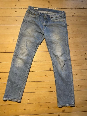 Levi's 502 ljusblå  jeans - Klassiska ljusblå 502 jeans från Levi's med slimfit passform och fem fickor. W33, L32. Jeansen har en vintagekänsla med subtila slitningar och den ikoniska läderpatchen bak i midjan. Tillverkade i slitstark denim med dragkedjegylf och knapp. 
