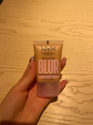 NYX Bare With Me Blur Foundation - NYX Bare With Me Blur Foundation i färgen 06 Soft Beige. Tuben är beige med rosa text och genomskinligt lock. Ger medium täckning och en matt, suddig finish. Perfekt för dig som vill ha en naturlig look med jämn hudton.