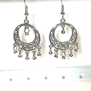 Silverfärgade runda örhängen  - Ett par silverfärgade örhängen med rund länk med ihåligt tibetan mönster och öronkrokar . 5cm längd 