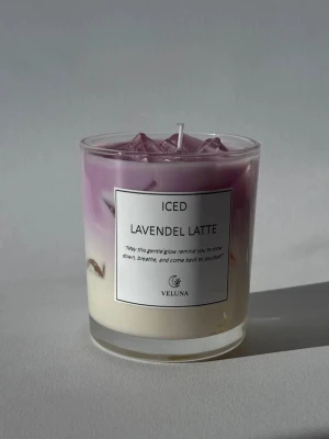 Lavendel latte doftljus i glas - Säljer ett snyggt doftljus från Veluna i glasbehållare. Ljuset har en tvåfärgad design i lila och vitt och är dekorerat med små lavendelbitar. Doften är lavendel latte och etiketten har ett inspirerande citat. Perfekt för att skapa mysig stämning hemma.
