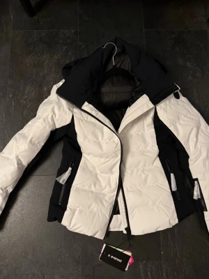 Vitt och svart set - Säljer ett par vinterkläder för väldigt bra pris, helt sprillans nya köpt i slutet av vintern så har ej använt dom, bara testat byxorna och märkte att dom va för små för mig så har inte blivit att jag har använt dom. Så helt splitt nya och aldrig använda, jackan är jätte fodrad och gör att den blir väldigt varm och skön, byxorna är väldigt mjukt material vilket gör dom stretchiga!💕💕Ifrån Everest och köpt på stadium!  Storlek S i jackan  Storlek 34/xs i byxorna Original pris 2700kr 💕💕