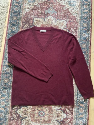 Paul & Friends v-neck - Vinröd oversize v-neck från Paul & Friends. Mjuk och fin tröja som är perfekt både för att ”dressa upp” med en vit skjorta under, eller för att ha mer casual med bara en vit t shirt under. Tröjan är använd fåtal gånger och är i storlek M, men med en oversize passform. Jag är 189cm för referens på bilderna.