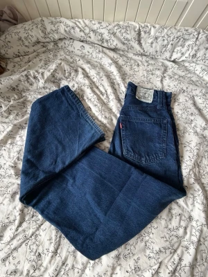 Levi's blå raka jeans - Säljer ett par klassiska marinblåblå Levi's jeans med  Lös passform och hög midja. Jeansen har femficksdesign, silvriga detaljer och röda Levi's-lappen på bakfickan. Tillverkade i marinblå slitstark denim som ger en tidlös look. DEM ÄR MARINBLÅ, MÖRKARE I VERKLIGHETEN!!!!! Passar w23-24, EUR 32-34 kanske en xs? Om du har eventuella frågor eller vill ha mått tveka inte att fråga! 💗  Pris kan ev. diskuteras 