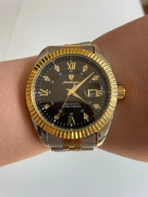 Svart och guld klocka från Poedgar - Den är använd men i bra skick har små små skador som bara syns om man kollar och känner någrant.Kommer med förlängningar