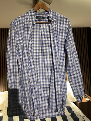 Blårutig skjorta från Polo Ralph Lauren - Säljer en blårutig skjorta från Polo Ralph Lauren i slim fit. Skjortan har klassisk krage, långa ärmar och knappar framtill. Tillverkad i mjuk bomull och passar perfekt för en clean och stilren look.