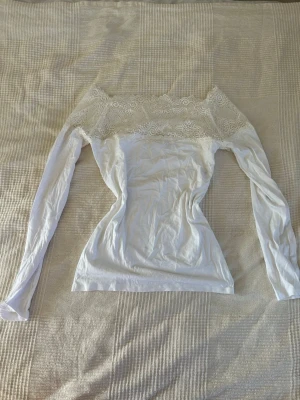 Vit spetsblus från MARTA - Supersöt vit blus från MARTA med långärmad design och bred spetsdetalj upptill. Offshoulder-modell som ger en romantisk vibe och passar perfekt till jeans eller kjol. Materialet känns mjukt och lätt, och spetsen ger en extra touch av elegans. Storlek S/M💗