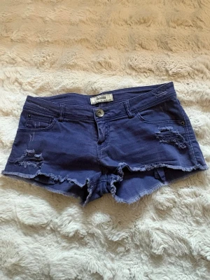 Blå/lila  jeansshorts från Bershka - Säljer ett par lila blå jeansshorts från Bershka med fransiga kanter och slitna detaljer.  I modellen är de ganska korta och väldigt lågmidjade, supersnygga💗💗