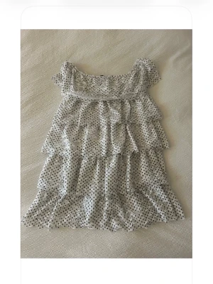 Vit prickig volangklänning Zara  - Supersöt kort vit klänning med svarta prickar och flera volanglager. Offshoulder-modell, storlek M men sitter som en S! 