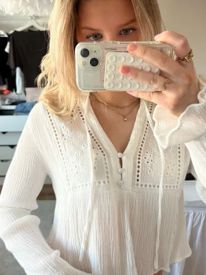 Vit blus från Zara - Söt vit blus från Zara med långa ärmar. Blusen har en avslappnad passform, v-ringning och lätt vågigt tyg som ger en bohemisk känsla. Perfekt att styla med jeans eller kjol för en trendig look. Storlek M men skulle säga mer att den sitter som en S/XS.