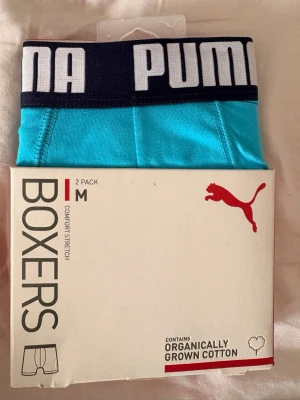Puma boxerkalsonger 2-pack blå M - Säljer ett 2-pack boxerkalsonger från Puma i storlek M. Ena paret är turkosblå med svart resår och vita bokstäver, det andra är mörkblå med ljusblå resår och vita bokstäver. Tillverkade i mjuk, ekologisk bomull med stretch för extra komfort.
