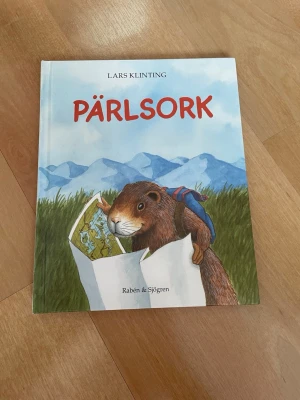 Pärlsork av Lars Klinting - Barnbok med färgglad illustrerad framsida där en sork med ryggsäck läser karta framför berg. Mjukpärm och tryckt av Rabén & Sjögren. Perfekt för dig som gillar mysiga berättelser och fina bilder.