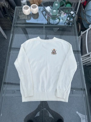 Morris stickad tröja vit bomull M - Säljer en stilren Morris stickad tröja i vit färg med broderad logga på bröstet. Klassisk och clean design som passar perfekt till både vardag och mer uppklädda outfits.  Storlek M. Material: 100% bomull – mjuk, bekväm och andas bra. Skick: mycket bra skick, inga hål eller större slitningar.  Perfekt preppy/old money vibe – funkar lika bra med jeans, chinos eller över en skjorta. En riktig garderobsbas 🔥 