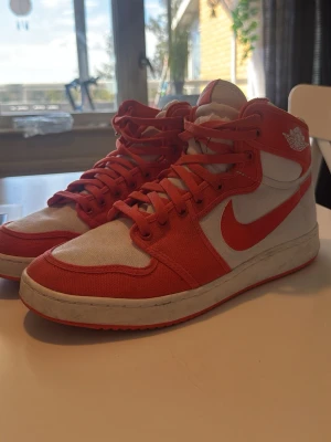Nike Air Jordan 1 High röd/vit - Säljer ett par Nike Air Jordan 1 High sneakers i orange och vitt. Skorna har klassisk hög siluett, orange swoosh och detaljer samt vitt tyg på sidorna. Ikonisk Air Jordan-logga på ankeln och röda snören. Perfekt för dig som gillar streetstyle och retro vibes. Jag är osäker på vad jag köpte dom för och har heller ingen original box till dom där av de låga priset.