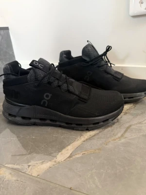 Svarta On Cloud-sneakers - Snygga helsvarta On Cloud-sneakers med diskret logga på sidan och hälen. Skorna har en chunky sula med On's karakteristiska CloudTec-dämpning och ovandel i mesh och syntet. Perfekta för dig som gillar stilrena och sportiga sneakers.