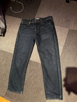 Mörkblå jeans från Jack & Jones - Snygga mörkblå jeans från Jack & Jones med klassisk femficksmodell och raka ben. Jeansen har kontrastsömmar och är tillverkade i slitstark denim. Perfekta för en avslappnad och trendig stil.