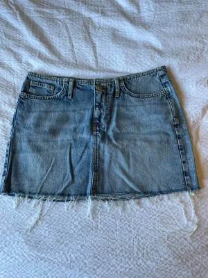 Blå jeanskjol från GinaTricot  - Snygg blå jeanskjol från GinaTricot med fransig  kant nertill. Använd ett fåtal gånger 