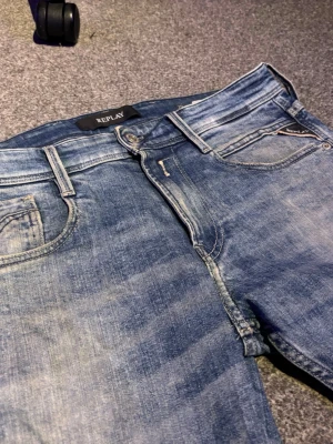 Replay jeans - Snygga blå jeans från Replay med klassisk femficksdesign och diskreta slitningar. Jeansen har normal midja, dragkedjegylf och läderpatch bak. Perfekta för en avslappnad och trendig look. Jeansen har en liten fläck på knät, med den går nog bort.