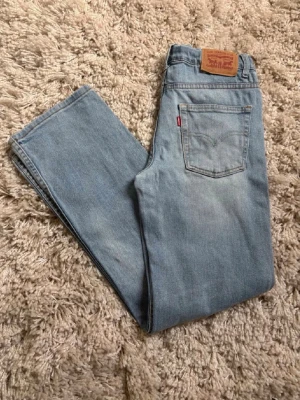 Ljusblå Levi's 551Z straight jeans - Säljer ett par ljusblå Levi's 551Z straight jeans med klassisk femficksdesign och läderpatch bak i midjan. Jeansen har raka ben och är tillverkade i slitstark denim med den ikoniska röda Levi's-taggen på bakfickan.
