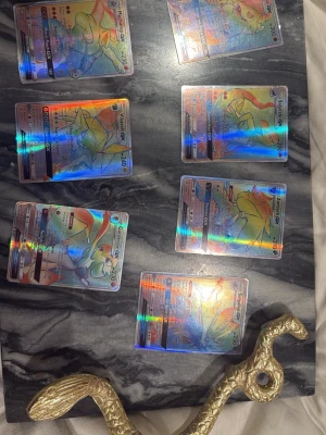 Pokémon GX holografiska samlarkort - Säljer ett set med sex Pokémon GX holografiska samlarkort. Korten har färgstarka och glansiga effekter med olika Pokémonmotiv. Perfekt för dig som gillar att samla eller spela Pokémonkort. Alla korten har en unik design och är placerade på en marmorerad bakgrund.