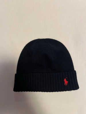 Marinblå mössa från Polo Ralph Lauren - Säljer en marinblå Polo Ralph Lauren mössa i nyskick, aldrig använt. Vid fler bilder/frågor är det bara att höra av sig.
