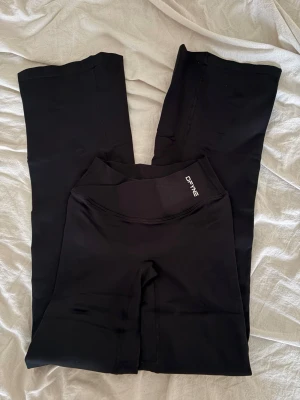 dfyne vision flares - Säljer ett par svarta leggings från DFYNE med hög midja och ribbad linning. De har en tight passform och är tillverkade i ett stretchigt material som formar sig efter kroppen. Perfekta för träning eller chill dagar. 