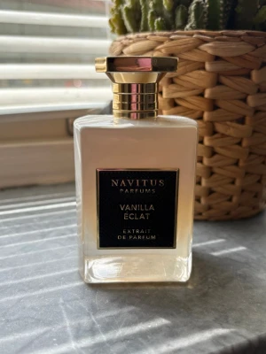 Navitus Vanilla Éclat parfym - Lyxig parfymflaska från Navitus Parfums med doften Vanilla Éclat. Flaskan är rektangulär i genomskinligt glas med svart och guldfärgad etikett samt en elegant guldfärgad kork. Extrait de Parfum för dig som gillar exklusiva vaniljtoner. Endast testad 
