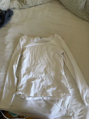 Vit långärmad topp - En enkel och stilren vit långärmad topp med rund halsringning. Tillverkad i mjuk bomull som känns skön mot huden. Perfekt att matcha med jeans eller kjol för en clean look.