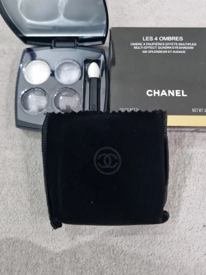 Chanel Les 4 Ombres ögonskugga - Chanel Les 4 Ombres ögonskuggspalett i nyansen 306 Splendeur et Audace. Paletten innehåller fyra skimrande nyanser i silver, grått och mörkgrått. Kommer i en elegant svart dosa med spegel och applikator samt en svart sammetsfodral med Chanel-logga.