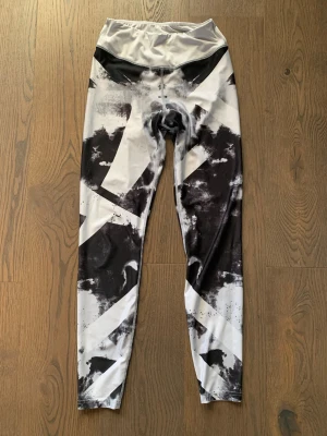 Svarta och vita tights med mönster - Säljer ett par snygga tights med högt midjeband och abstrakt svartvitt mönster. De är stretchiga och är perfekta för träning. Materialet känns mjukt och följsamt mot huden. Inga fickor eller synliga loggor.