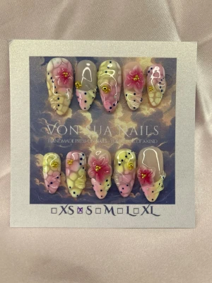 Hana (S);Medium Almond - Handgjorda press-on naglar i en medium lång mandelform. Designen har en mix av pastellgul, rosa och nude med 3D-blommor, gulddetaljer och mörkblåa/ljusa prickar. Perfekt för dig som vill ha unika och konstnärliga naglar med mycket detaljer.S: 15 mm, 11,5 mm, 12 mm, 11 mm, 9 mm 