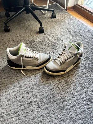 Air Jordan 3 ”Chlorophyll” stl 45,5 - Säljer ett par Air Jordan 3 Jordan 3 ”Chlorophyll” sneakers i grått med vita snören och gröna detaljer. Storlek 45,5. Skorna har en klassisk design med en mellanhög silhuett och en mönstrad sula.