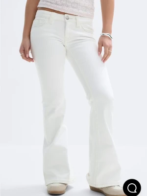 Vita bootcut jeans med låg midja - Säljer ett par vita bootcut jeans med låg midja och klassiska fem fickor. Jeansen har utsvängda ben och stängs med knapp och dragkedja. Stl 170, uppsprättade där nere, passar typ upp till 170cm 
