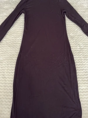 Svart långärmad poloklänning - En svart långklänning med lång ärm och polokrage. Klänningen har en enkel, rak passform och är tillverkad i ett mjukt, stretchigt material som känns bekvämt mot huden. Perfekt för dig som gillar minimalistisk stil.