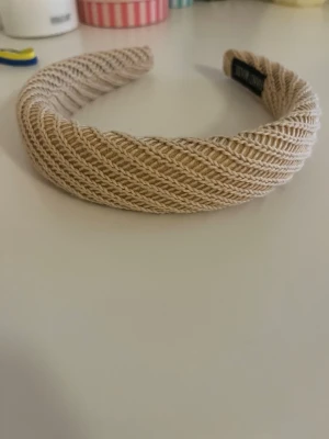 Beige stickat diadem - Snyggt beige diadem med stickad struktur och bred form. Perfekt accessoar för att lyfta din look med en trendig touch. Mjukt material som sitter bekvämt på huvudet och ger en avslappnad men ändå stilren vibe.