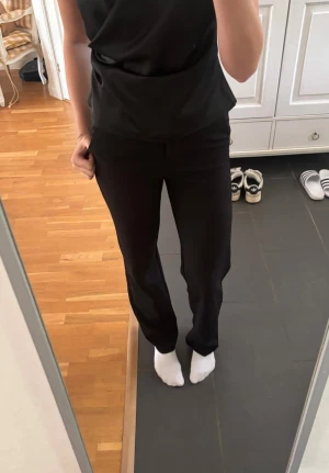 Kostymbyxor  - Snygga svarta kostymbyxor med raka ben och hög midja. Byxorna har diskreta fickor i sidorna och en klassisk passform som ger en clean look. Perfekta till en stilren outfit och passar till många olika tillfällen. Storlek Xs/34