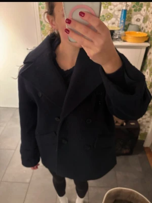 Mörkblå dubbelknäppt ullkappa - Snygg mörkblå kappa med dubbelknäppning och bred krage. Klassisk modell med två framfickor och rak passform. Perfekt för kyliga dagar och lätt att matcha med olika outfits. Overzised i modellen 💕
