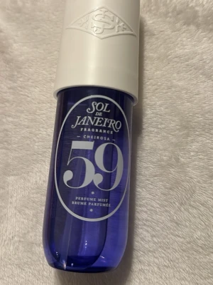 Sol de Janeiro Cheirosa 59 Perfume Mist - Sol de Janeiro Cheirosa 59 Perfume Mist i en snygg lila plastflaska med vit kork. Flaskan har en modern, rundad form och tydlig logga framtill. Perfekt för dig som gillar fräscha och unika dofter med en trendig look.