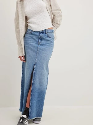 Lång jeanskjol med slits från NA-KD - Trendig lång jeanskjol från NA-KD i ljusblå denim med hög midja och rak passform. Kjolen har en snygg slits framtill och rå kant nertill för en avslappnad vibe. Klassiska fickor både fram och bak samt knapp- och dragkedjestängning.