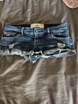 Blå jeansshorts från Hollister - Säljer ett par blå jeansshorts från Hollister med låg midja och klassiska gula sömmar. 