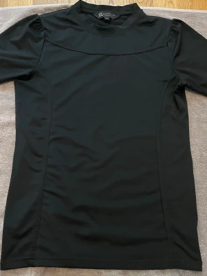 Rid T-shirt  - Svart rid T-shirt från kingsland. Man ser märket på sidan av armen och har en krona på baksidan av T-shirten 