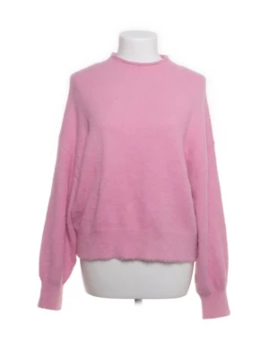 Ljusrosa fluffig stickad tröja - Mysig ljusrosa stickad tröja med rund hals och långa ärmar. Tröjan har en fluffig, mjuk struktur och ribbade muddar vid ärmslut och nederkant. Perfekt för dig som gillar en avslappnad och trendig look.