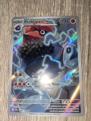 Pokémonkort Probopass Holo - Säljer ett holografiskt Pokémonkort med Probopass från Scarlet & Violet-serien. Kortet har färgstarka detaljer i blått, rött och grått med el-effekter och är nummer 096/088. Perfekt för samlare eller dig som vill stärka din kortlek.