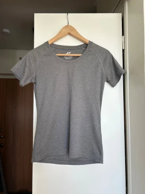 Grå träningströja från PRO TOUCH - Snygg grå kortärmad träningströja från PRO TOUCH. Tillverkad i ett lätt och snabbtorkande funktionsmaterial som passar perfekt till gymmet eller löprundan. Tröjan har rund halsringning och en smal passform.